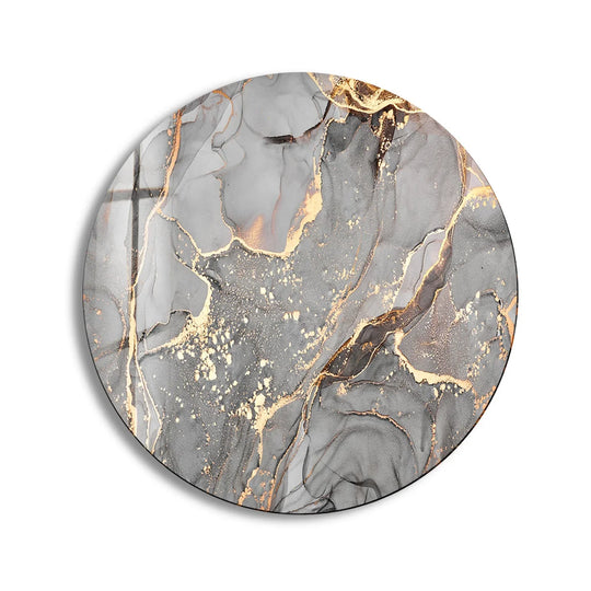 The organic forms of gray and gold blend within the round glass wall artwork, creating a striking marble effect with fluid, abstract patterns.