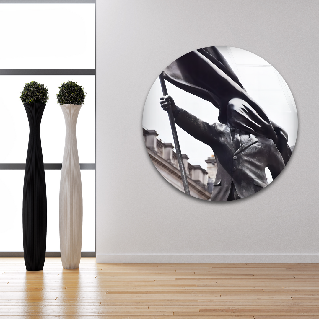 The background reveals bright, tall windows and a minimalist white wall, providing a stark setting for the Banksy Flag Bearer glass art.