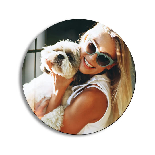Smiling woman wearing sunglasses hugs her dog close, showcasing a vibrant and personalized print on glass photo framed within the round custom wall art.
