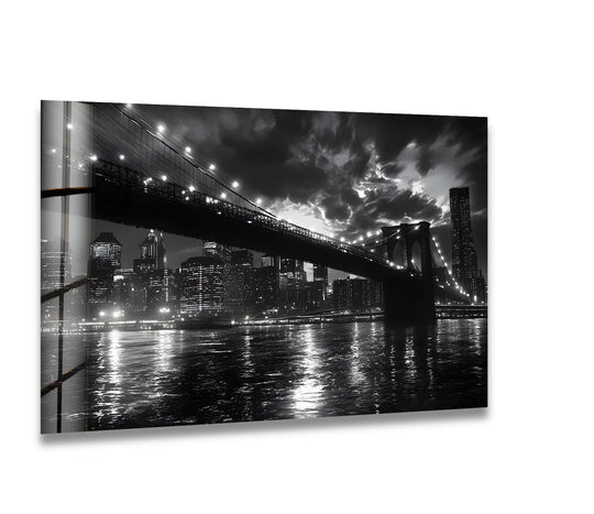 Striking color contrast highlights the illuminated Brooklyn Bridge and cityscape against the dark sky in this black and white glass printing wall art.
