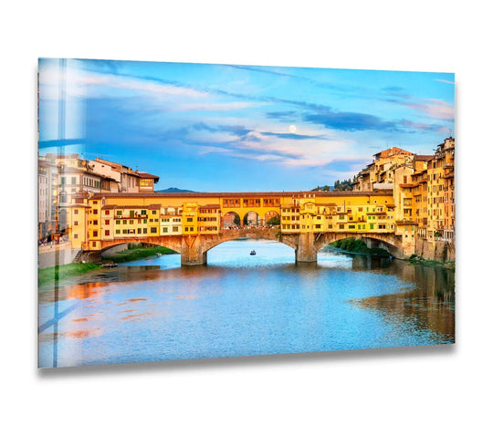 Vibrant yellow buildings atop the Ponte Vecchio bridge create the loudest element in this striking Florence glass wall artwork over the Arno River.