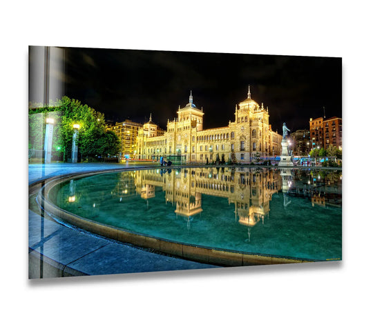 Striking color contrast illuminates the Valladolid historic building and its vivid night reflections, presented as captivating art from glass.