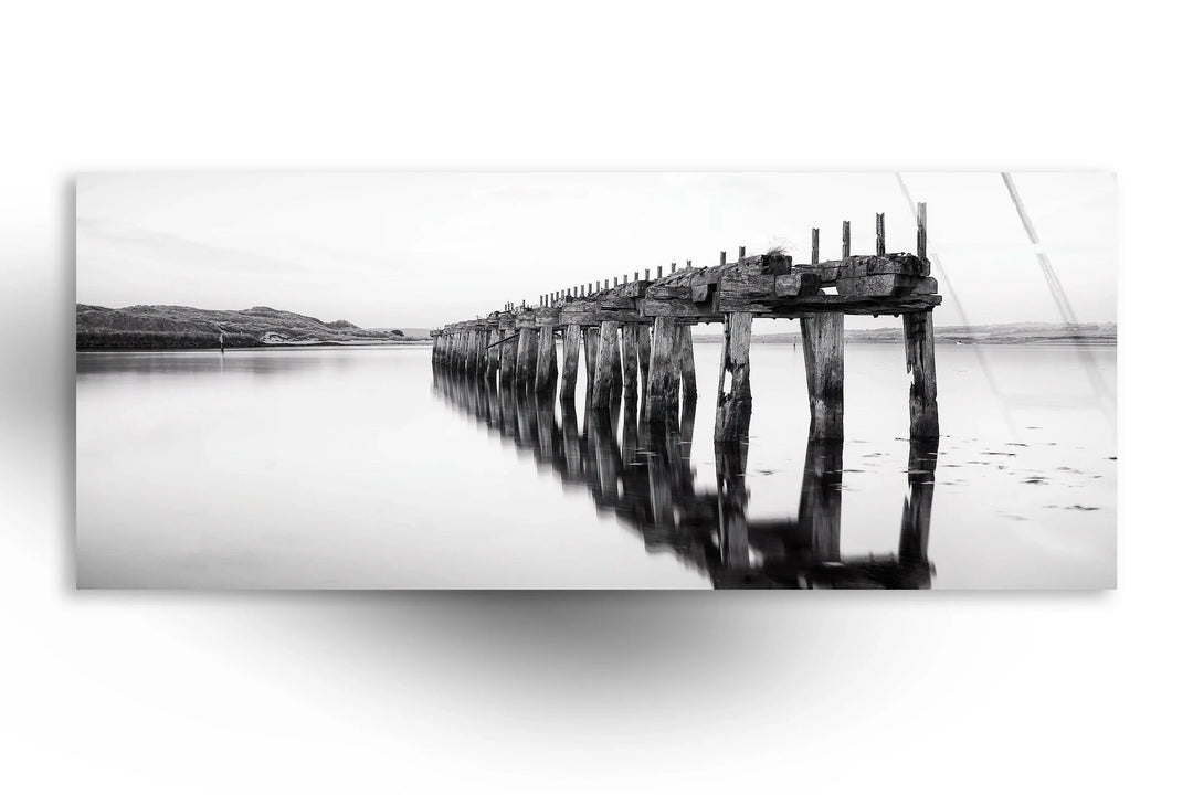 Minimalist monochrome landscape showcasing a weathered pier stretching over still waters.