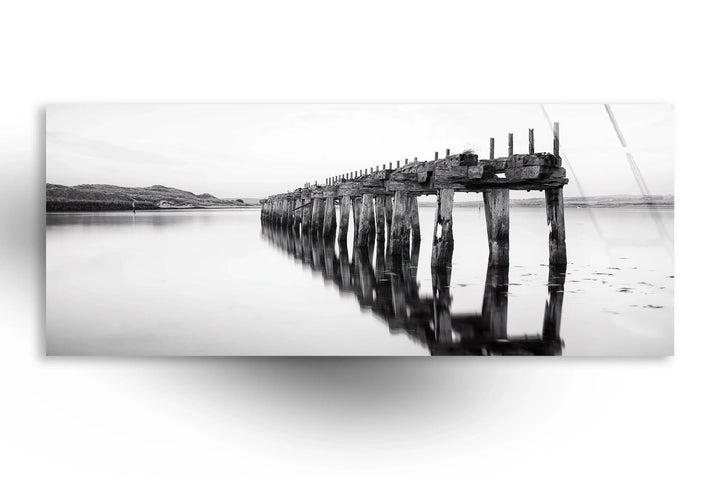 Minimalist monochrome landscape showcasing a weathered pier stretching over still waters.