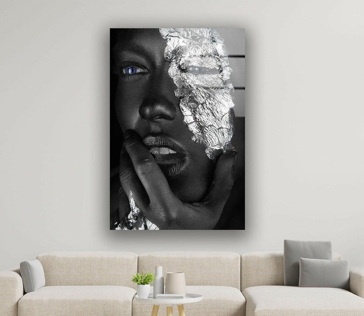 Black and white glass wall art featuring a close-up face with metallic silver texture and vivid blue eyes.