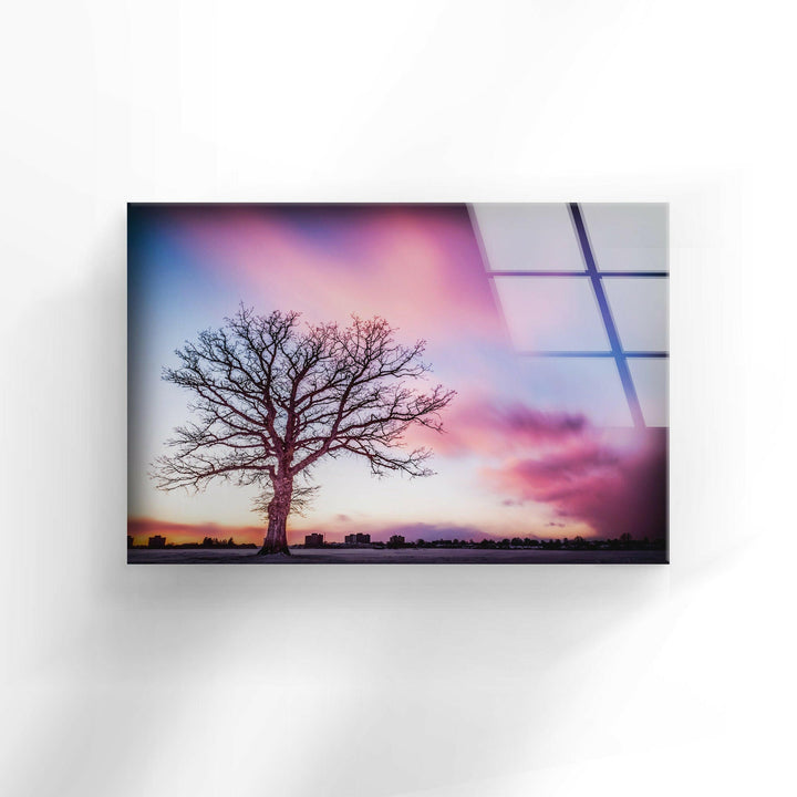Breathtaking glass wall art of a solitary tree silhouetted against a colorful evening sky.
