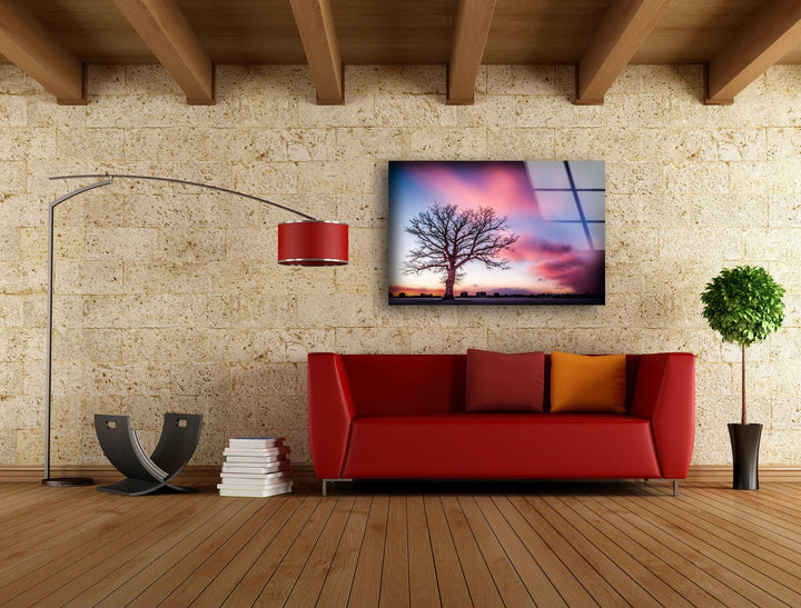 Elegant glass wall art showcasing a bare tree at dusk with dramatic clouds.
