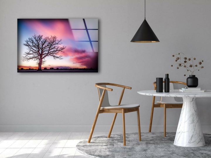 A serene glass wall art piece featuring a sunset-lit sky and a solitary tree.
