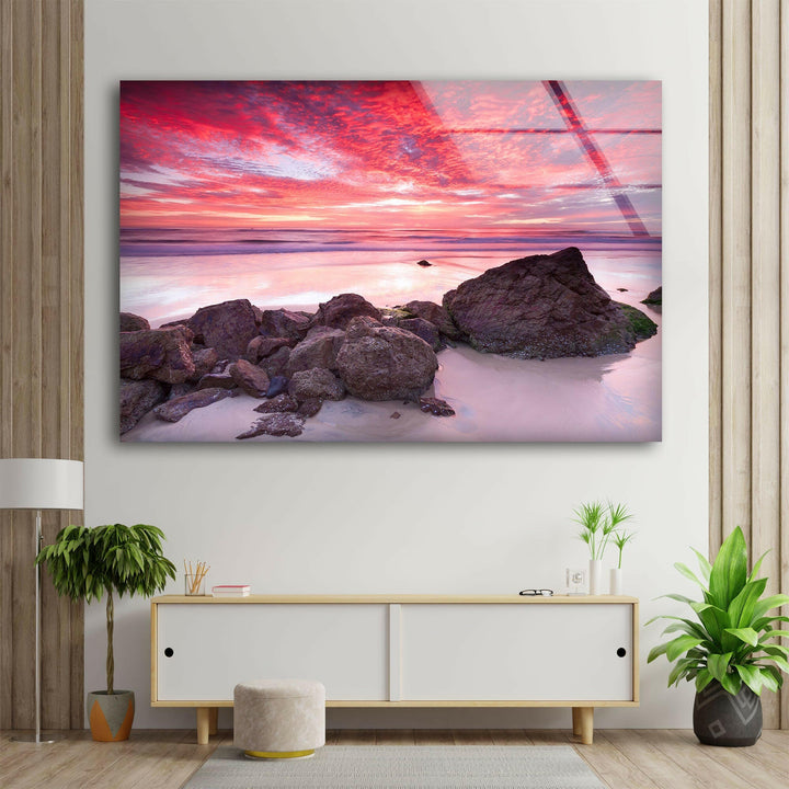 Dramatic sky reflecting on the ocean at sunset, framed by rocky formations.
