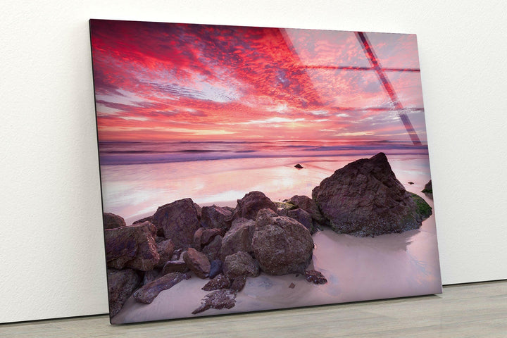 Rocky beach bathed in soft pink hues of a breathtaking sunset.
