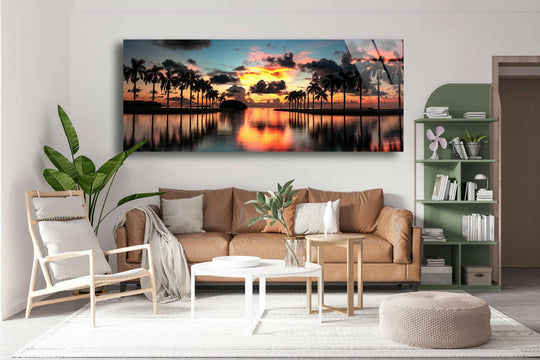 Miami Deering Estate sunrise glass wall art showcases a vibrant panoramic landscape and fiery orange reflections above a calm water surface in a living room