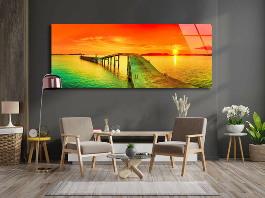 Pier and Sunset Seascape glass wall art showcases a long pier extending into golden waters and a vibrant sunset and offers modern wall decor for a living room