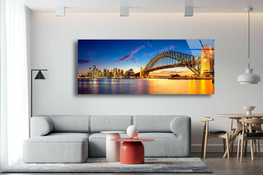 Curving lines of the Harbor Bridge contrast with the organic forms of the cityscape in this panoramic glass art painting showcasing a vibrant night scene.