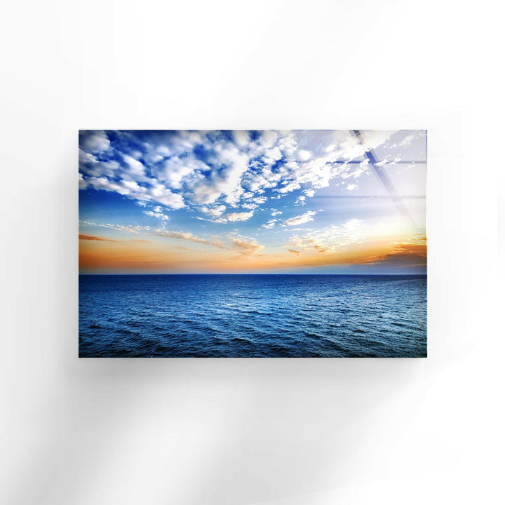 Sunset over the endless sea, reflecting vibrant hues of blue and gold on glass wall decor.
