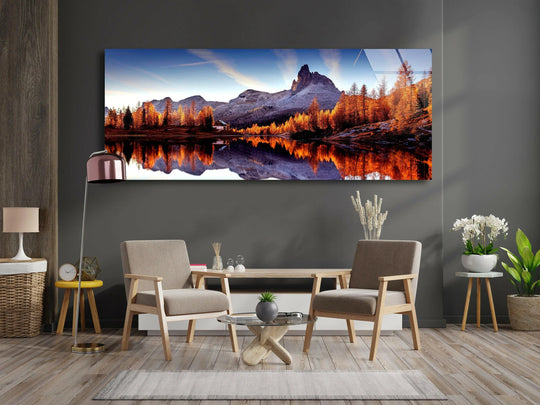 Mountain Lake landscape glass wall art showcases a reflective scenic view and golden trees with a mountain backdrop above a wooden sideboard in a living room
