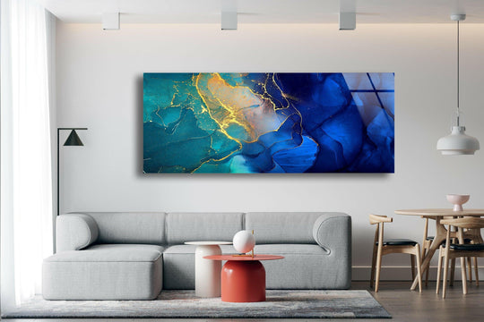 Blue and gold marble abstract glass wall art features a swirling design and gold accents above a gray sofa in a living room