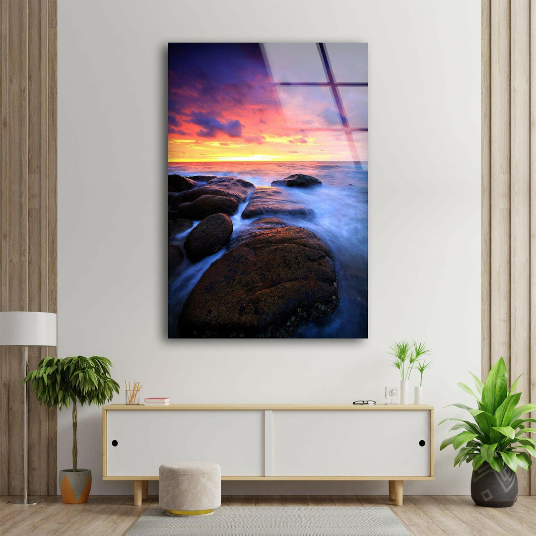 Coastal landscape with glowing twilight hues and misty water effect on glass wall art.
