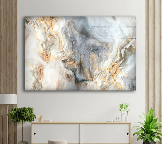 Fluid swirls of gray, white, and gold create a mesmerizing visual rhythm in this abstract glass wall art print.