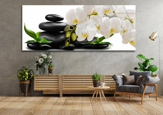 Zen Stones and White Orchid glass wall art displays a calming floral and stone arrangement and offers modern wall decor for a tranquil living room