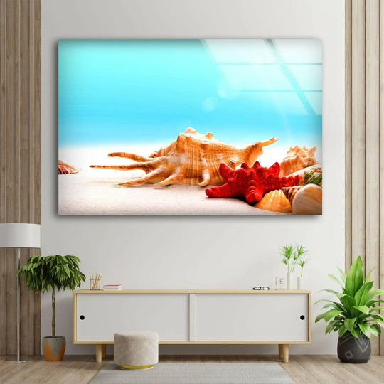 Smooth, reflective tempered glass wall art highlights the grainy surface texture of the sand and intricate details of seashells and a starfish in this coastal scene.