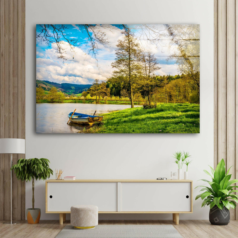 Serene nature artwork showcasing a rustic boat resting by the calm river under a bright blue sky.
