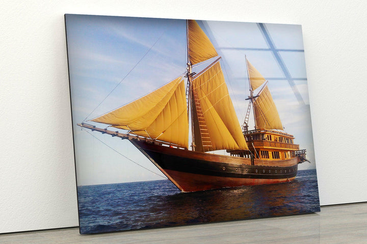 Golden-sailed wooden ship navigating calm waters under a serene sky, displayed on tempered glass.
