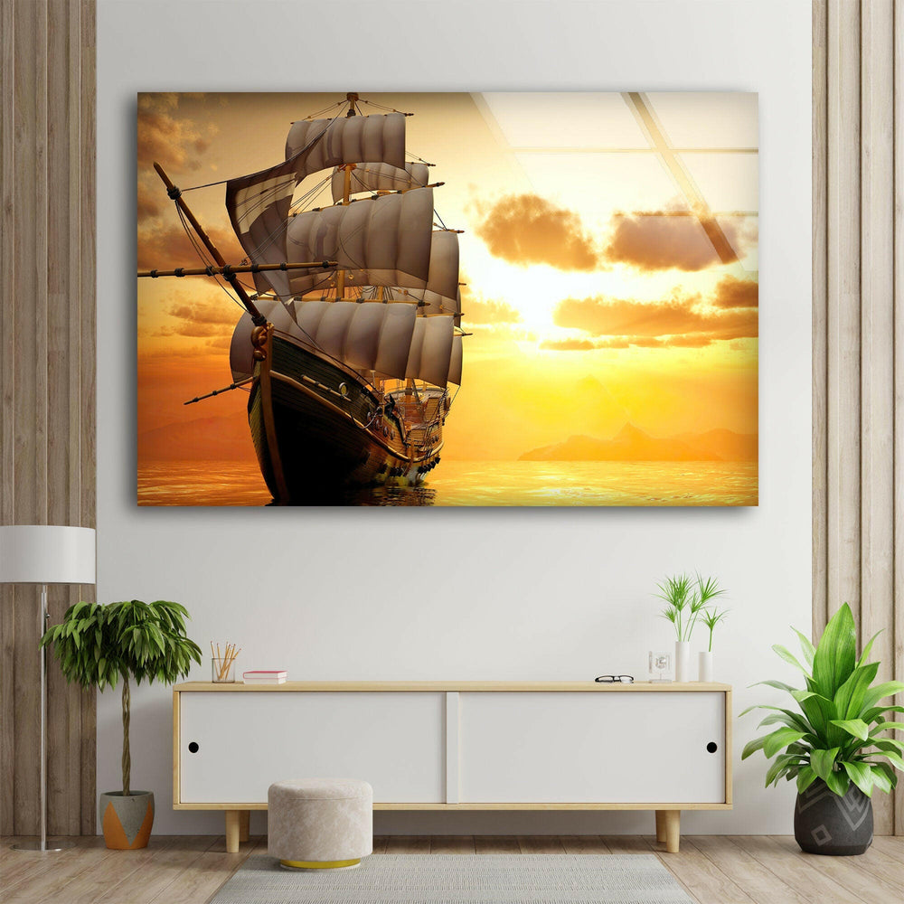 Nautical-themed glass wall art featuring a classic sailing ship against a breathtaking sunset.

