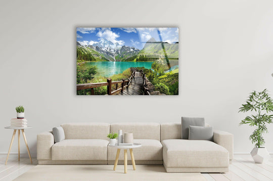 Gradual shifts in color define this scenic mountain lake glass print wall art, where deep greens meet turquoise waters beneath the snow-capped peaks.