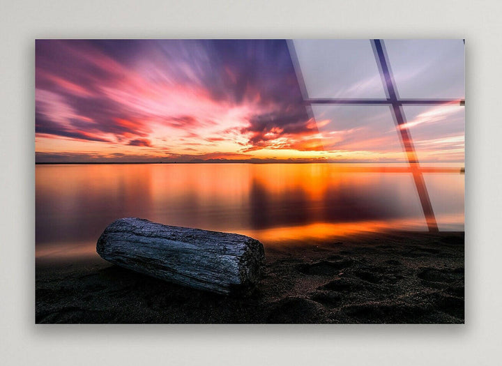 Stunning sunset over the ocean with a weathered log resting on the shore.
