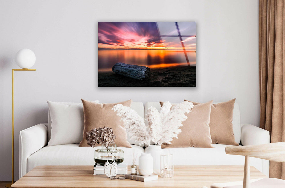 Vibrant sunset hues mirrored on the shoreline, creating a peaceful scene.
