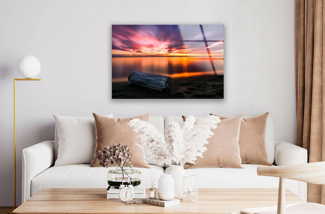 Vibrant sunset hues mirrored on the shoreline, creating a peaceful scene.
