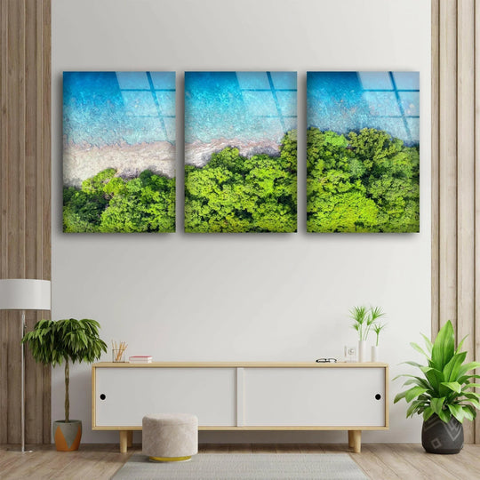 Tropical beach and forest bird's eye view glass wall art shows an ocean scene and a coastal motif for a modern wall decor statement and a tropical theme