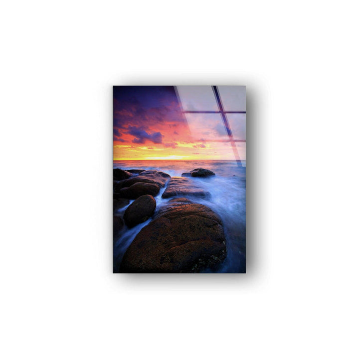 Dramatic ocean horizon at dusk, showcasing a vivid sky and textured rocks on glass wall art.
