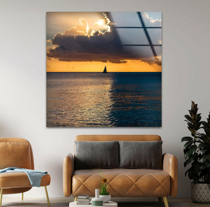 A relaxing ocean sunset scene with a sailboat set against a glowing golden sky.
