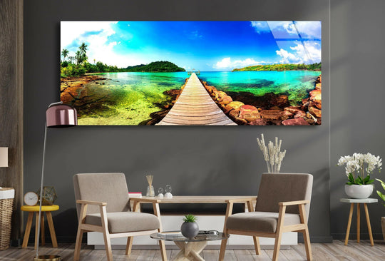 Tropical Beach With Wooden Dock glass wall art showcases a scenic landscape and vibrant turquoise waters with a long wooden dock extending towards a lush island modern wall decor and large wall art for a living room
