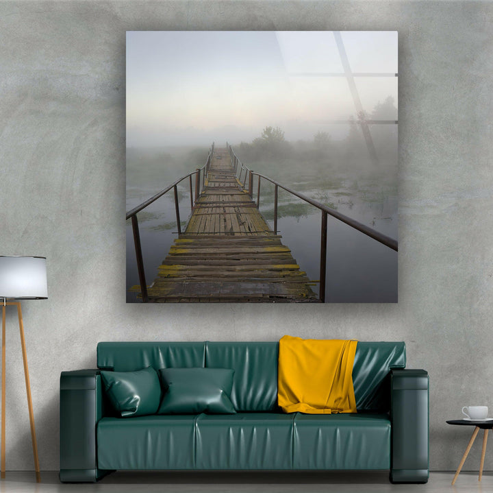 Early morning fog draping over a wooden bridge and calm water, creating a dreamy ambiance.

