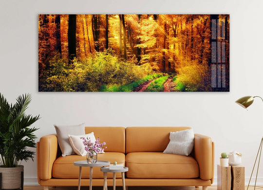 Negative space frames a vibrant forest landscape, showcasing the beauty of sunny autumn as a captivating glass art painting on a wall above a modern couch.