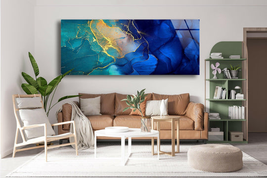 Blue and gold marble abstract glass wall art features a swirling design and gold accents above a brown sofa in a living room