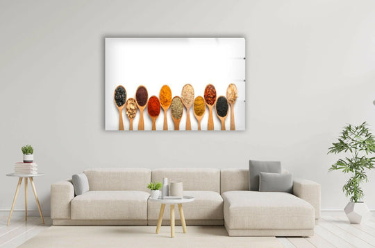 Horizontal glass wall art featuring wooden spoons filled with colorful spices displayed above a neutral sofa in a bright living room.