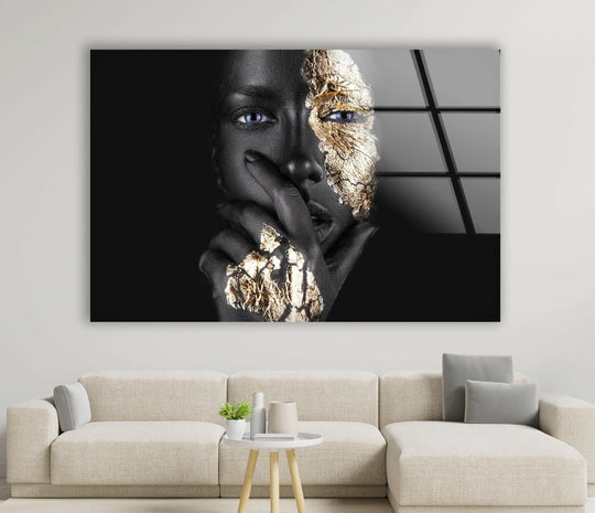 A woman's face is split between matte black skin and cracked, textured gold leaf in this striking wall print.