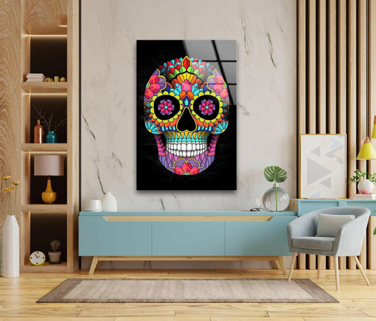 A vertical rectangular glass wall art print showcases a vibrant, colorful, floral-patterned skull against a dark background.