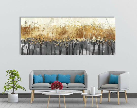 Golden Trees panoramic glass wall art features a stunning abstract landscape and golden hues with silhouetted trees above a gray base in a modern living room