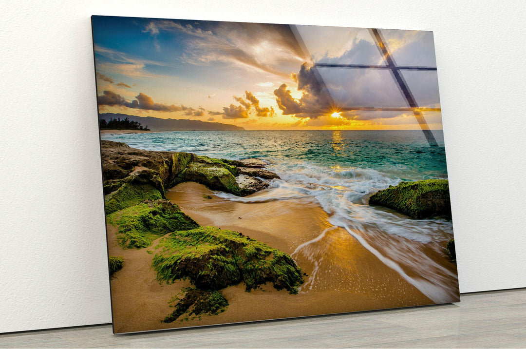 Rocky coastline at sunset, illuminated by golden sunlight reflecting off the water.
