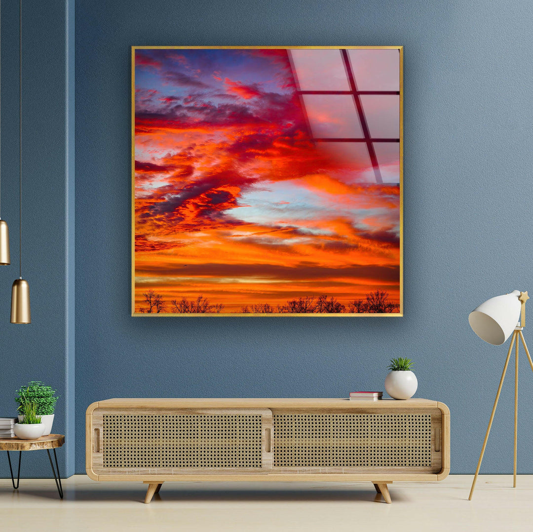Stunning glass wall art featuring a vivid red and orange sunset over a peaceful horizon.
