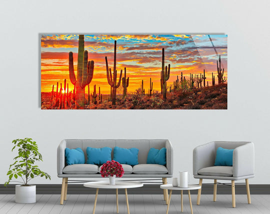 Sunset at Sonoran Desert glass wall art features silhouetted cacti and a vibrant orange sky and is a stunning panoramic landscape decor for a large wall above a sofa