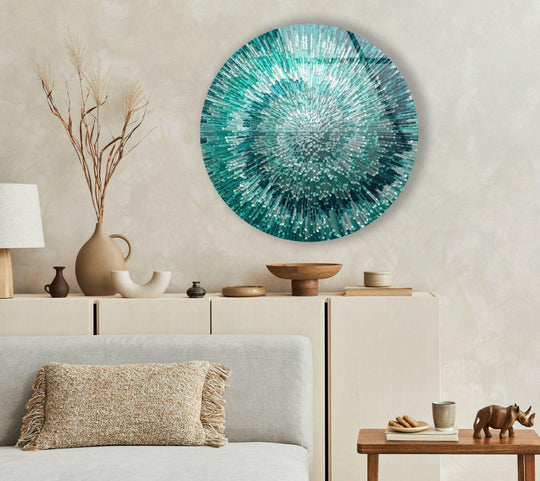 The brightest area of the round silver and green glass art painting explodes with shimmering light and vibrant turquoise hues.