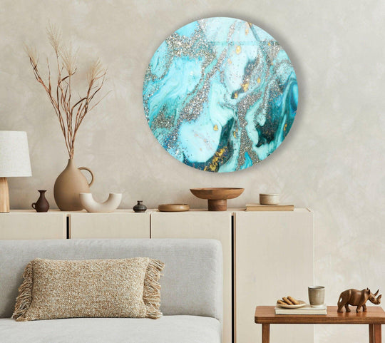 Neutral backdrop accentuates the negative space surrounding a round glass hanging wall art piece featuring a blue marble design with striking silver details.