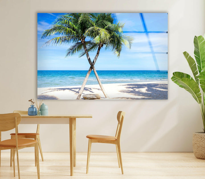 Coastal-inspired glass wall art displaying a sunlit beach, palm trees, and a deep blue horizon.
