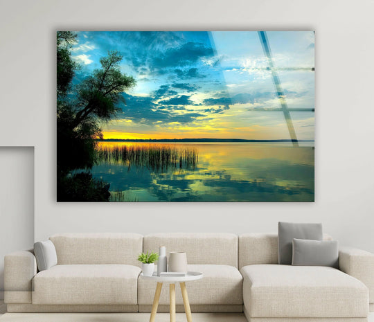 Serene lake scene at sunset with golden hues and calm water reflections on glass.
