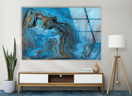 Lustrous decorative wall art showcases the premium quality of this glass print's swirling blue and gold alcohol ink design.